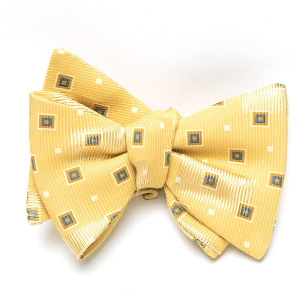 A yellow bow tie with white and blue squares on it.