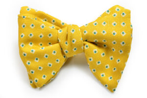 A yellow bow tie with white and green flowers.