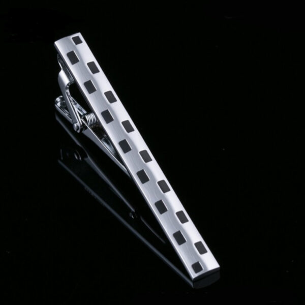 A silver tie bar with black squares on it.