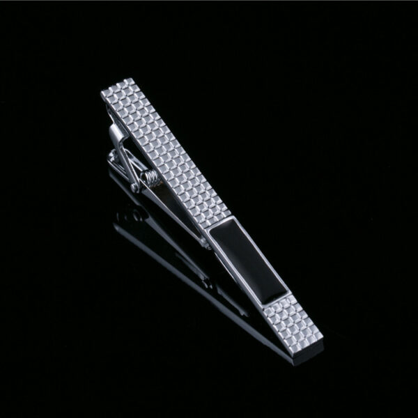 A silver tie clip with black and white design.